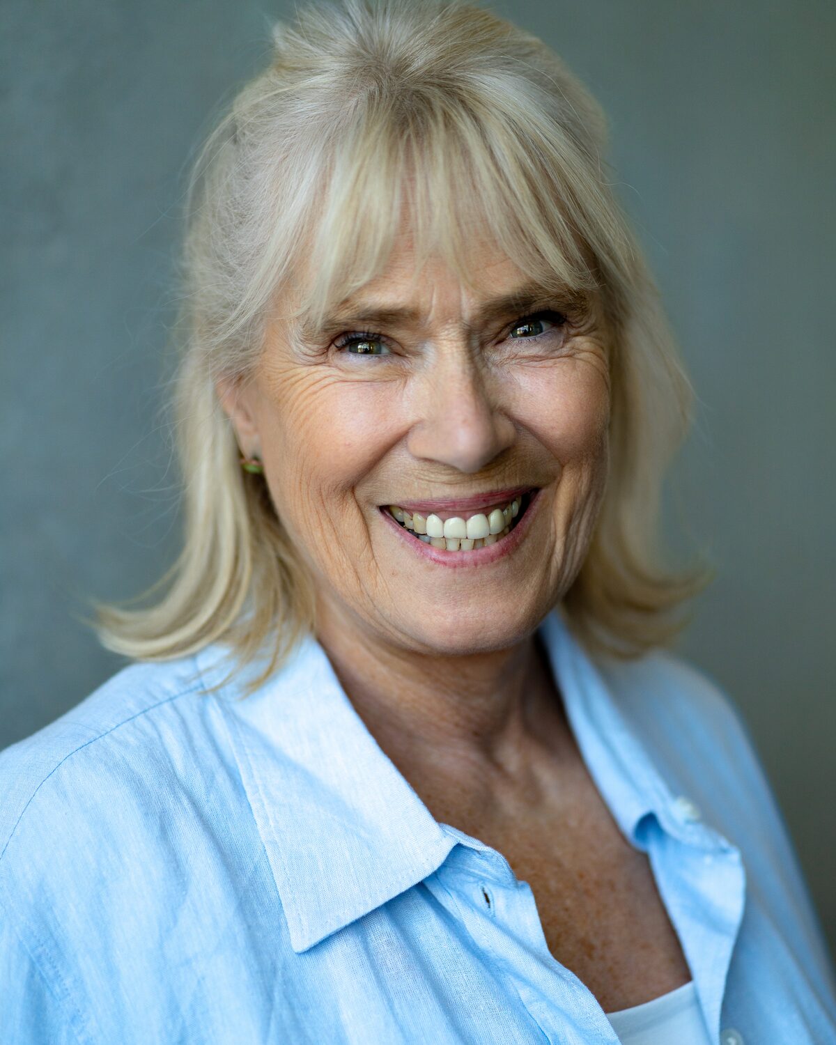 Headshot of Maggie Saunders smiling, in a blue shirt